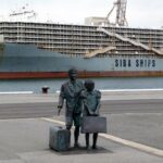 Monumento à emigração japonesa: família de imigrantes com malas em porto, navio ao fundo